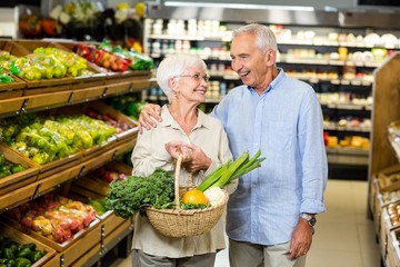 Smiling senior couple holding basket with vegetables