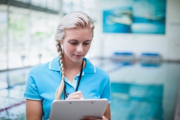 Pretty trainer writing on clipboard