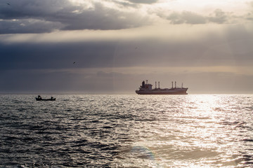 Cargo ship sailing on sunrise near the beach