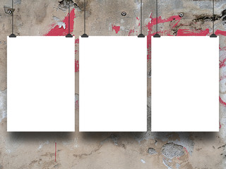 Close-up of three hanged paper sheets with black clips on graffiti wall background