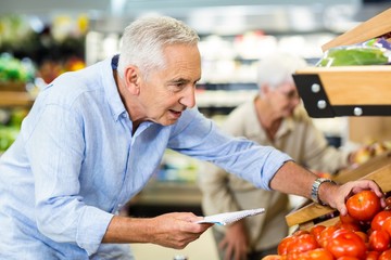 Smiling senior man with list buying apple