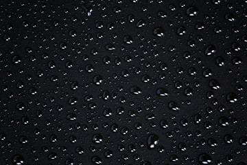 water drops on a black plastic surface, dark background