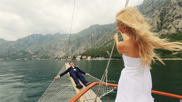 Happy wedding couple having fun on the stern of the ship 