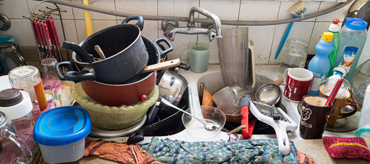 Pile of dirty utensils in a kitchen washbasin