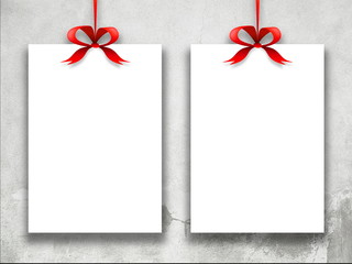 Close-up of two hanged paper sheets with red ribbons weathered wall background