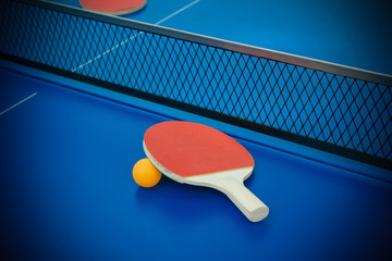 pingpong rackets and ball highlighted on a blue pingpong table
