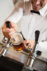 Handsome barman pouring a pint of beer