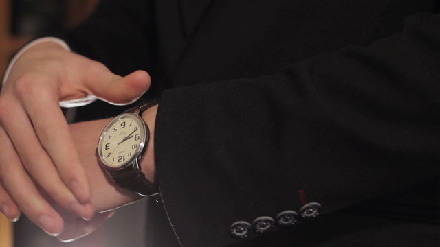 Male businessman puts his hand on the clock