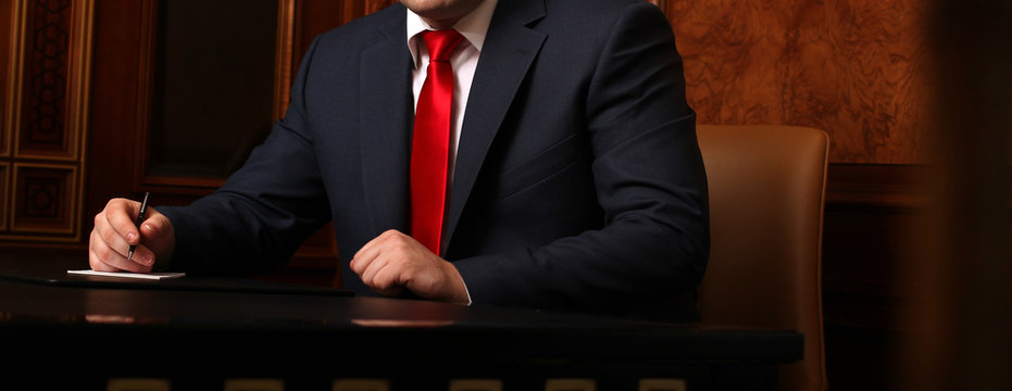 Close up of businessman sitting at table and signing document