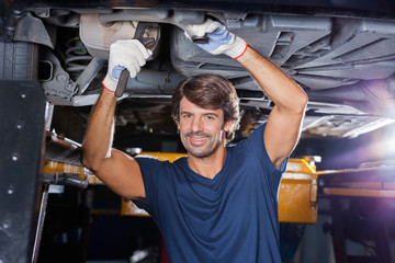 Mechanic Working Under Lifted Car At Garage