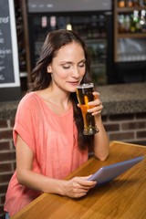 Pretty woman having a beer and looking at tablet