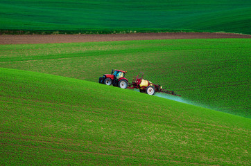 Farm machinery spraying insecticide to the green field, agricultural natural seasonal spring...