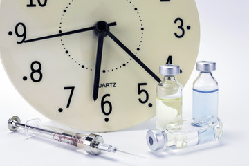 medicine vials and syringe, the clock shows the time of the medi