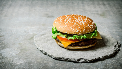 Fresh Burger with cheese and meat on a stone stand.