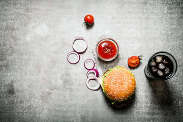 hamburger with tomato ketchup and soda on stone table.