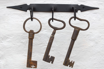 three medieval iron keys on a white wall