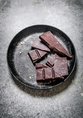 Bitter chocolate in the old pan. On stone background.