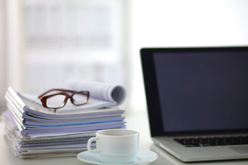 a stack of papers on the desk with a computer