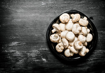 Fresh mushrooms on the plate. On black rustic background.