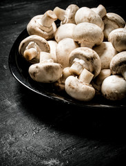 Fresh mushrooms on the plate. On black rustic background.