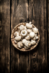 Fresh mushrooms in basket. On wooden background.