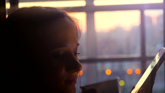 woman use mobile phone in city cafe at night on blurred architecture bokeh and road background. 4k