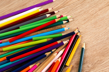 Colorful heap of pens on wooden table