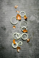 Fototapeta na wymiar Rings of fresh onions with husk . On stone background.