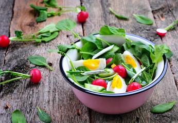 Salad with cucumber, radish, ramson, spinach, boiled eggs and olive oil.