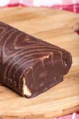 Chocolate roll cake on the kitchen wooden board