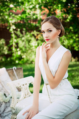 Beautiful romantic woman in light dress posing in a blooming gar