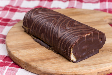Chocolate roll cake on the kitchen wooden board