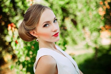 Naklejka premium Beautiful romantic woman in light dress posing in a blooming gar