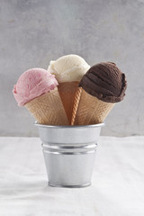 Strawberry, vanilla and chocolate ice cream cones and scoop.