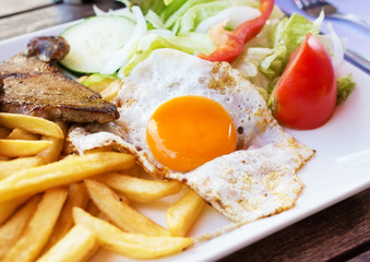 Fototapeta na wymiar Fried egg with potato fries, grilled steak.