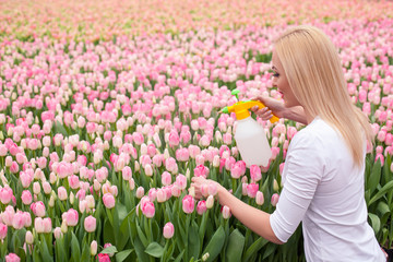 Obraz na płótnie Canvas Cheerful female gardener is working with flowers