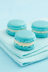 Three turquoise macarons with buttercream filling on oven mitt