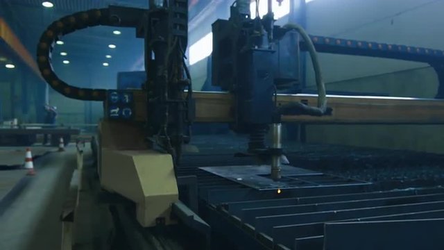 CNC plasma cutter is cutting out metal objects in a heavy industry factory. Shot on RED Cinema Camera.