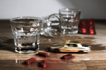 Mini car crash. Vodka shot, meting pills and speeding toy car on a table - metaphor of drunk driving. 