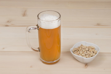 Draft beer and peanuts in the bowl on wood table