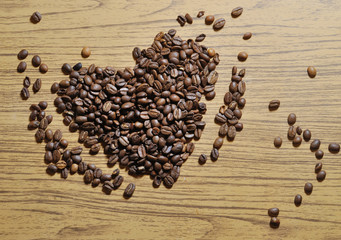 photo of heart shaped heap of coffee beans on wood background