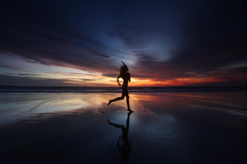 Woman running on the beach at sunset