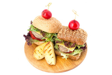 Two burgers on wooden cutting board