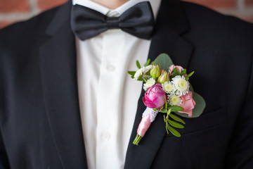 Close up of  white and pink rose corsage. Beautiful boutonniere pinned on man in black suit, white...