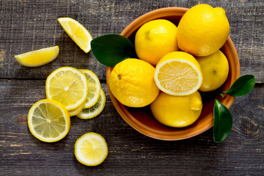 Fresh lemons in a bowl on a wooden table