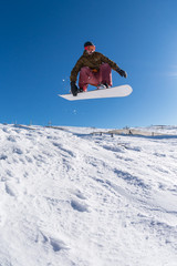 Naklejka na ściany i meble Snowboarder jumping against blue sky