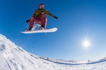 Snowboarder jumping against blue sky