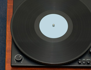 Part of vintage record player with wood finish with black LP vinyl record top view horizontal photo closeup