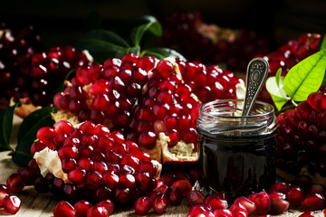 Homemade pomegranate jam in a glass jar with a spoon, fresh open