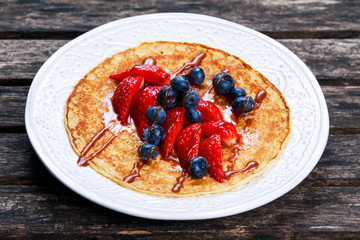 Fresh golden pancakes with strawberries, blueberries and chocolate.